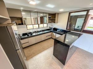 a large kitchen with a black counter top in it at Casa com 4 suítes, piscina, a 20m do mar| Milagres in Barra do Camaragibe