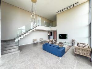 ein Wohnzimmer mit einem blauen Sofa und einer Treppe in der Unterkunft Casa com 4 suítes, piscina, a 20m do mar| Milagres in Barra do Camaragibe