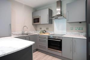 cocina con armarios blancos y fogones en Modern 2-Bedroom with balcony en Belfast