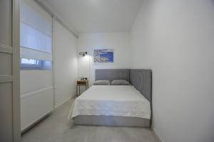 a white bedroom with a bed and a window at Apartman Ivan in Posedarje