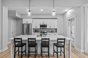 una cocina con una gran isla blanca con sillas negras en Beautiful Green Door Brownstone, en Jersey City