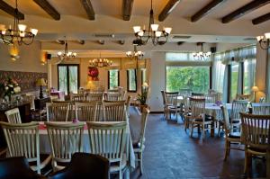 a restaurant with white tables and chairs and windows at Melegos Inn Hotel in Karpenisi