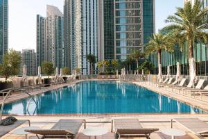 a swimming pool with chairs and palm trees and buildings at Kabene Exotic, Burj Khalifa & Fountain View, 5 Starts, 4 Bedroom, Best In Dubai in Dubai