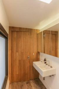 La salle de bains est pourvue d'un lavabo et d'un mur en bois. dans l'établissement Vn Al Campinas Refugio Moderno, à São Paulo