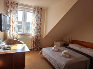 a bedroom with a bed and a tv and a window at Pensjonat Wioletta in Ostrołęka