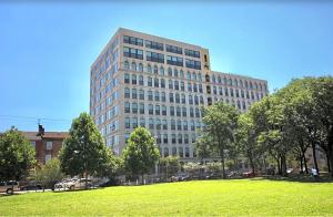Un edificio alto con un campo verde delante. en Nice 1 Bdrm Luxury Flat, en Filadelfia