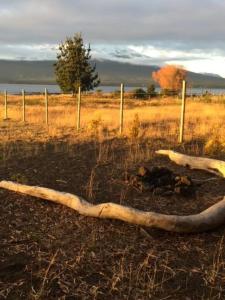 a log laying on the ground next to a fence at Espectacular casa orilla de lago in Puerto Varas