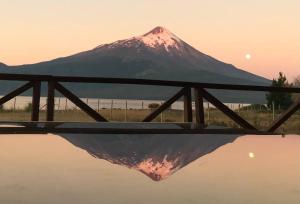 a mountain in the background with a reflection in the water at Espectacular casa orilla de lago in Puerto Varas