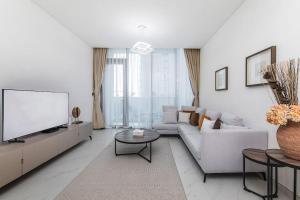 a living room with a couch and a tv at Aesthetic 1Br Chrystal Lagoon in Dubai