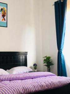 a bedroom with a bed with purple sheets and a window at Casa Homes Apt2 with unlimited Wi-Fi in Kampala +12 photos