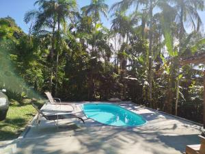 a swimming pool with a chair and a table and chairs at Sítio La Paz in Morretes +19 photos