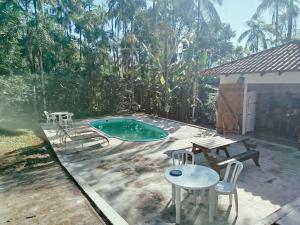 a small pool with a table and chairs and a picnic table at Sítio La Paz in Morretes