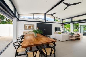 Twin Villas Natai - 7 Bedroom Luxury Beach Front Villa في شاطئ ناتاي: غرفة معيشة مفتوحة مع طاولة وكراسي خشبية