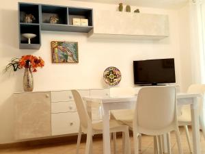 a dining room with a white table and a tv at I CACTUS di MiMa in Milano Marittima