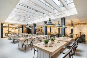 un restaurante con mesas, sillas y luces colgantes en Sercotel EsteOeste, en Lugo