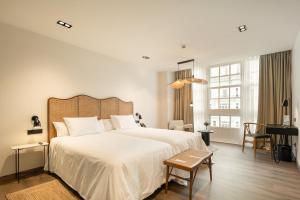 Un dormitorio con una gran cama blanca y un escritorio. en Sercotel EsteOeste, en Lugo