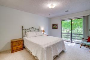 a bedroom with a bed and a window and a chair at Bella Vista Townhome with Deck Near Back 40 Trail! in Bella Vista