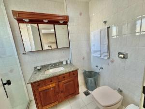 a bathroom with a sink and a toilet and a mirror at Apartamento no centro com varanda e vaga de garagem in Nova Friburgo +24 photos