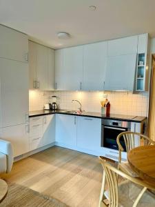 une cuisine avec des armoires blanches et une table et une chaise dans l'établissement Nordisk moderne leilighet med parkering, à Tomasjorda