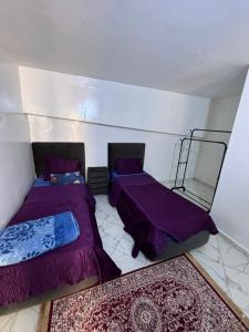 2 camas en una habitación con edredones púrpura en Villa avec piscine 2 chambres 2 salon 1 cuisine et piscine privée, en Bouznika