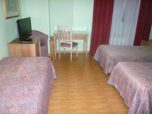 a hotel room with two beds and a table with a television at Hotel Ascot in Binasco