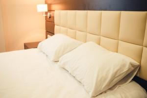 - un lit avec des draps et des oreillers blancs dans l'établissement Ostrovsky Hotel, à Kazan