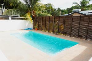 a swimming pool in front of a fence at bas de villa splendide in Rivière-Salée