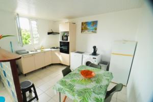 a small kitchen with a table and a refrigerator at bas de villa splendide in Rivière-Salée