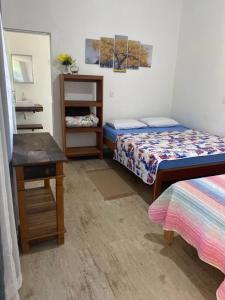 a small room with two beds and a table at Pousada Chalés Praia Vermelha in São João Batista do Glória