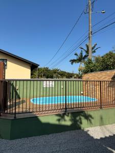 a metal fence with a pool in a yard at Morada das Orquídeas in Guarda do Embaú