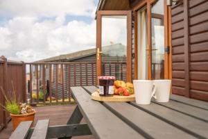 a picnic table with food and two cups on a balcony at 5 Ocean View in Woolacombe