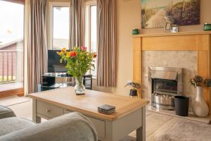 a living room with a fireplace and a table with flowers at 5 Ocean View in Woolacombe