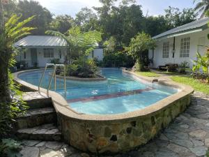 a swimming pool with a stone wall around it at Maya's Nest in Nagcarlan