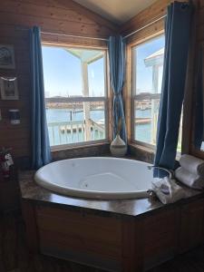 a large tub in a bathroom with a view of the ocean at Westport Marina Cottages in Westport