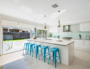 a kitchen with a large island with blue stools at Seachange Family Escape with Pool and Spa Bath in Saint Leonards