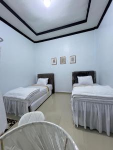 two beds in a room with blue walls at Acc Family Homestay in Takengon