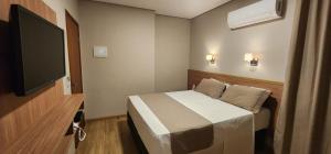 a bedroom with a bed and a flat screen tv at HOTEL BARU in Padre Bernardo