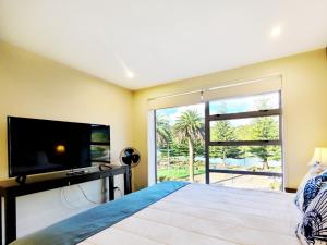 a bedroom with a large bed and a large window at Hosts on the Coast Harbour View at Esplanade Apt 111 in Whitianga +12 photos