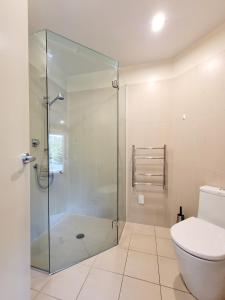 a bathroom with a glass shower and a toilet at Hosts on the Coast Harbour View at Esplanade Apt 111 in Whitianga