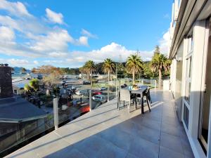 a balcony with a table and a view of a harbor at Hosts on the Coast Harbour View at Esplanade Apt 111 in Whitianga