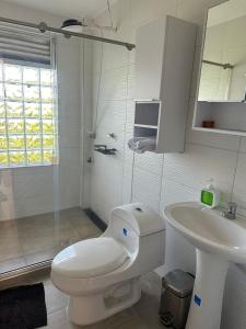 a white bathroom with a toilet and a sink at Casa Blanca in Quinchía