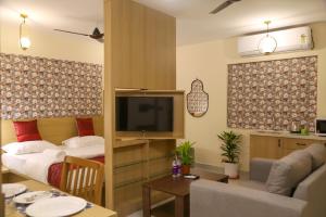 a living room with a couch and a tv in a room at Lumis studio apartment in Hyderabad +2 photos