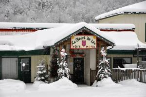 un restaurante cubierto de nieve con un cartel. en Le Boisé du Lac en Mont-Tremblant