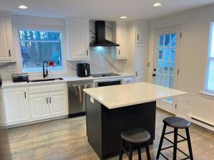 a kitchen with white cabinets and a counter and stools at 5min Gillette Stadium! Sleeps 12 in Norfolk