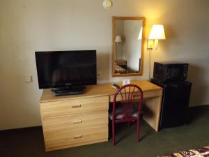 Habitación con escritorio, TV y silla. en Executive Inn Kilgore, en Kilgore