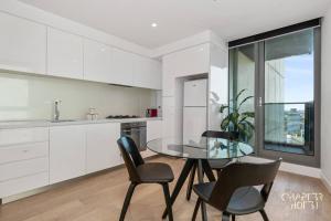 una cucina con tavolo in vetro e 2 sedie di Chapter 3 in Imagine Macro Hotel a Melbourne
