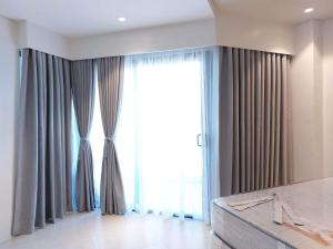 Schlafzimmer mit einem großen Fenster mit Vorhängen in der Unterkunft Tambuli Seaside Residences Buyong Road Maribago Lapu Lapu City in Cogon + 8 Fotos