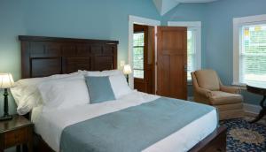 Green LakeにあるGreenway House Bed and Breakfastの青いベッドルーム(大型ベッド1台、椅子付)