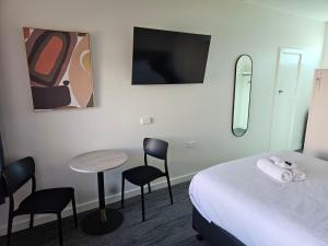 a hotel room with a bed and a table and chairs at International Hotel Motel in Port Pirie +2 photos