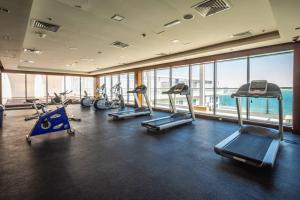 a gym with several tread machines in a room with windows at Contemporary Full Ocean View Apartment in Ras al Khaimah